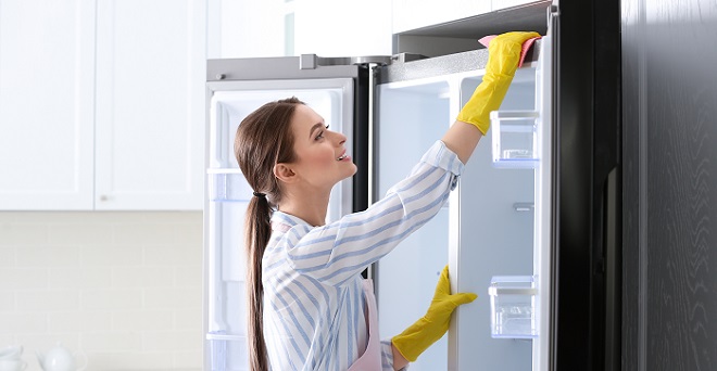 Homeowner cleaning and maintaining the fridge image