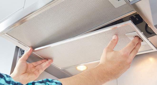Image of homeowner cleaning the grease filter in a range hood