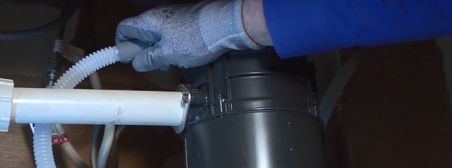Image of installer connecting the dishwasher drain line to the garbage disposal