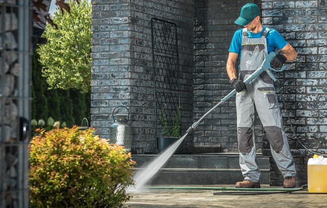 Image of a homeowner pressure washing the patio