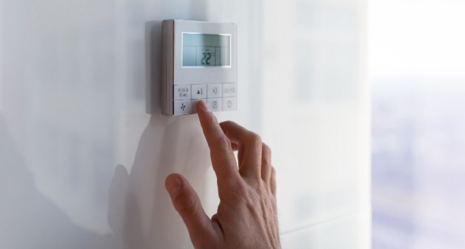 Image of homeowner adjusting thermostat for travel.