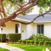 White ranch house with beautiful lawn, garden and tree in front yard